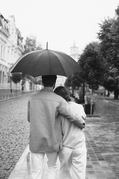 Пара, вид сзади, идущая под дождем