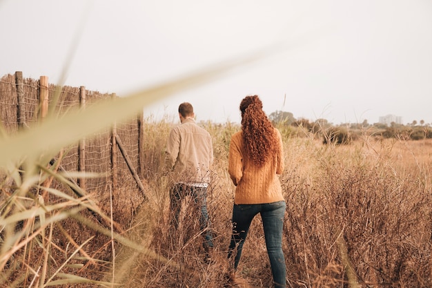 Back view couple walking through wheat field