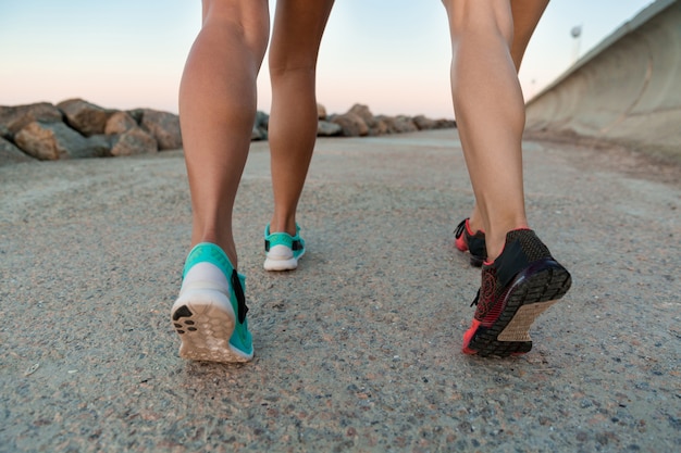 Back view cropped image of two young women in sneakers