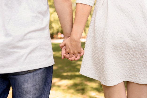 公園で手を繋いでいるかわいいカップルの背面図