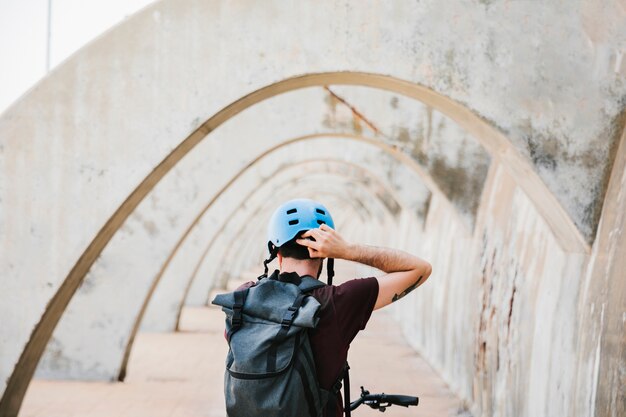 Back view of a cyclist putting on his helmet