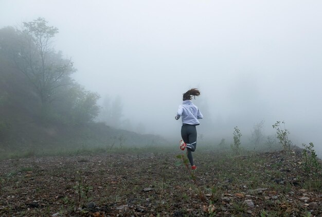 Вид сзади на решительного бегуна, бегущего по природе в туманную погоду