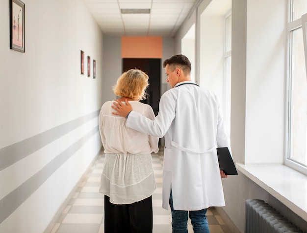 Free photo back view doctor and senior woman walking