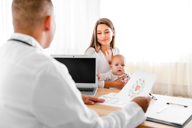 Back view doctor talking to mother of a baby