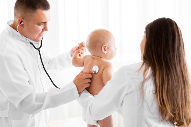 Вид сзади врачей с новорожденным ребенком