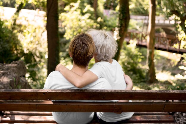 ベンチから公園の景色を眺めながら抱きしめるカップルの背面図