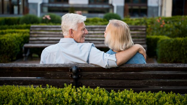 Back view of embraced older couple outdoors on bench