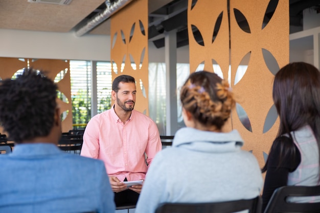 Free photo back view of employees listening to young consultant