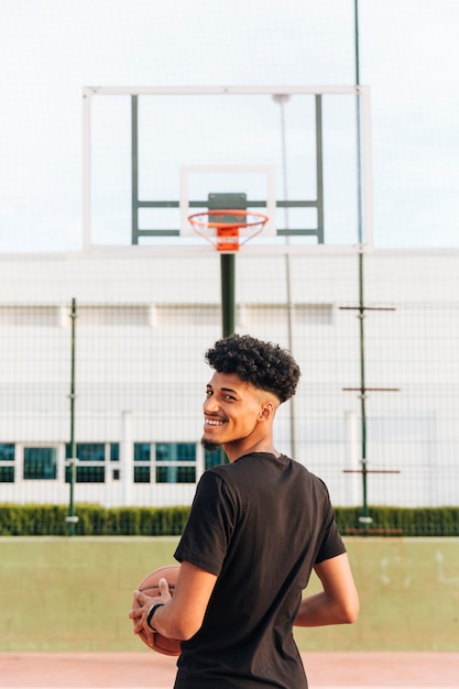 Back view of ethnic cheerful young man on basketball court 