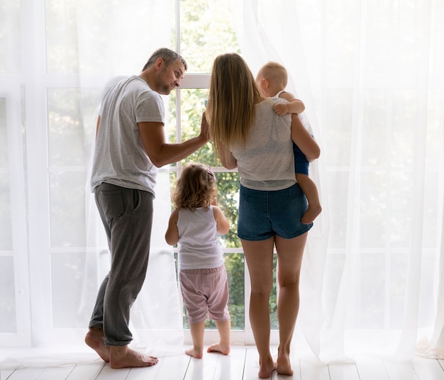 Vista posteriore membri della famiglia guardando fuori dalla finestra