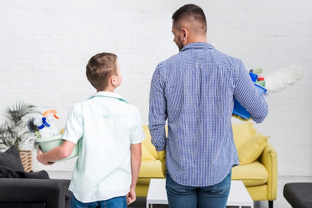 Back view of father and son posing with cleaning products