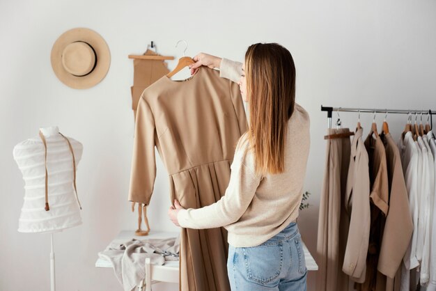 Back view of female tailor checking garments