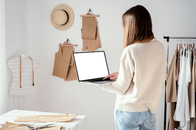 Back view of female tailor in the studio using laptop