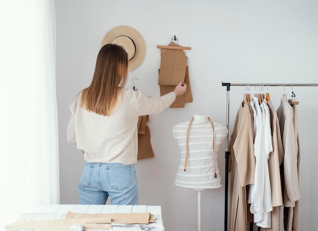 Back view of female tailor in the studio with clothes