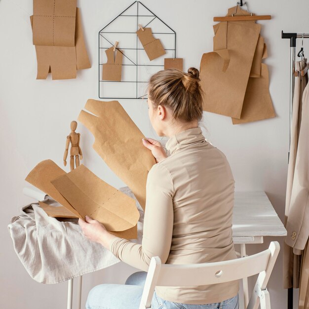 スタジオでパターンに取り組んでいる女性の仕立て屋の背面図
