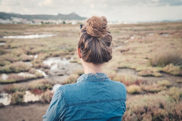 畑に座っているお団子ヘアの女性の後ろ姿