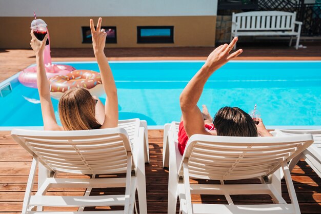 Back view friends in beach loungers