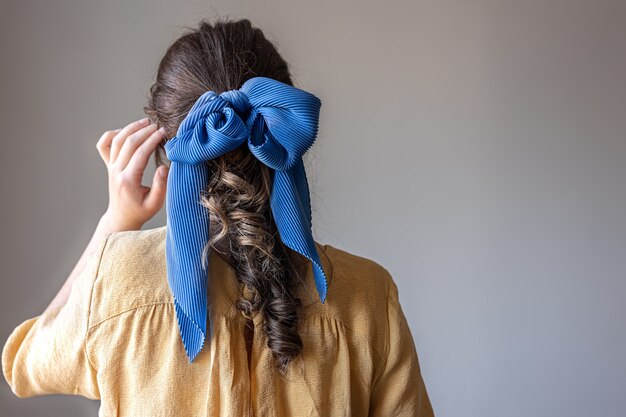 Back view a girl in a dress with a bow in her hair on a gray background