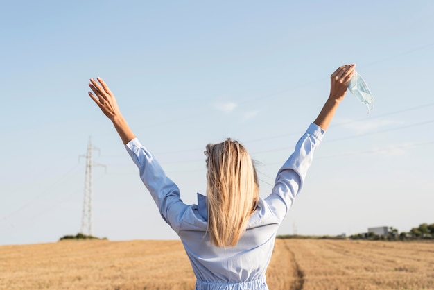 Ragazza di vista posteriore che rimane con le braccia alzate