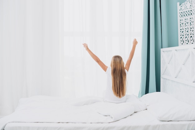 Free photo back view girl stretching after waking up