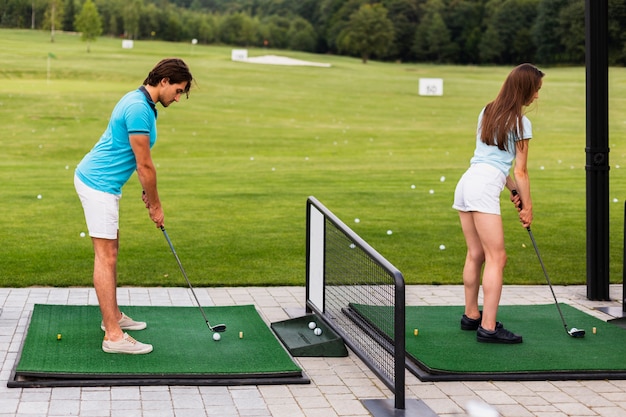 Бесплатное фото Задний вид игроков в гольф, практикующих свинг