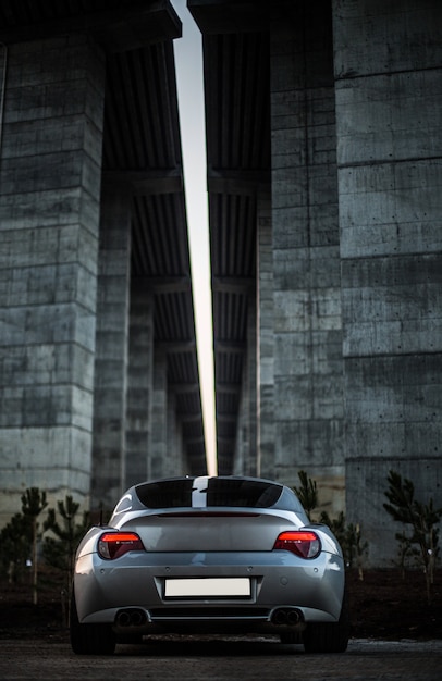 Задний взгляд серого автомобиля стоя под мостом.