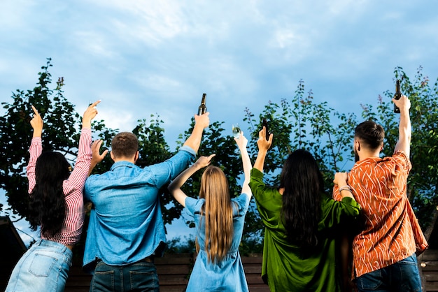 Free photo back view group of friends raising hands