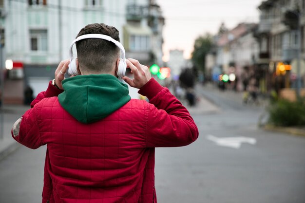 ヘッドフォンと暖かい服を着て背面図男 無料の写真
