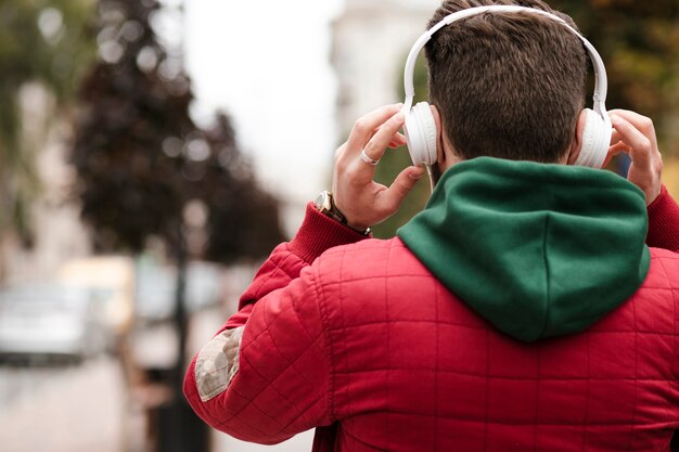 Back view guy with headphones and warm jacket