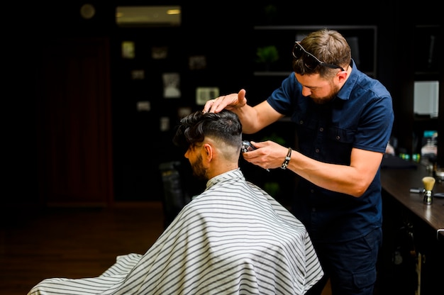 Back view hairstylist cutting costumer's hair