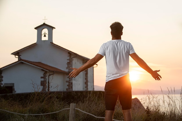 Vista posteriore bel viaggiatore maschio che si gode il tramonto