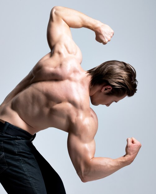 セクシーな筋肉の美しい体のポーズでハンサムな男の背面図。