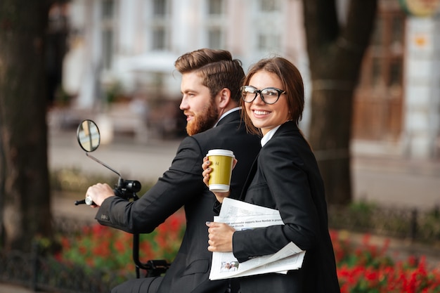 Back view of happy elegant couple rides on modern motorbike