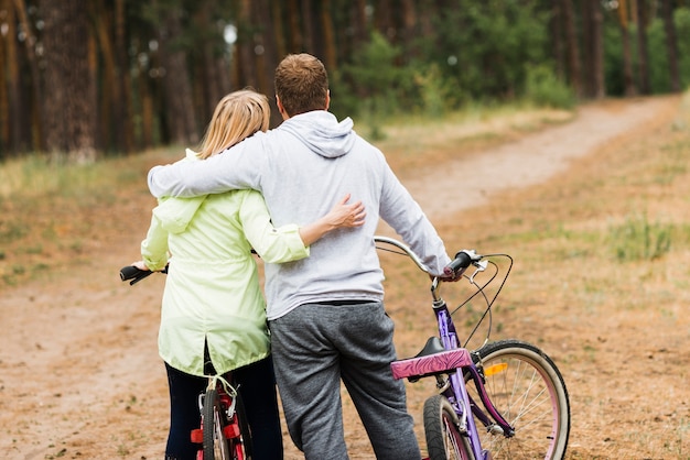 Free photo back view hugging couple with bicycles