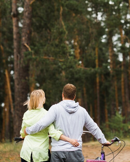 Back view hugging couple with forest background