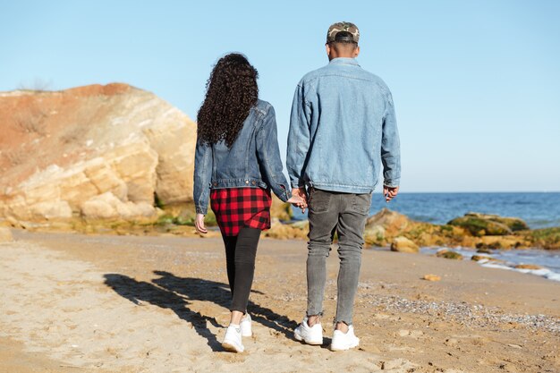 Back view image of african loving couple walking outdoors