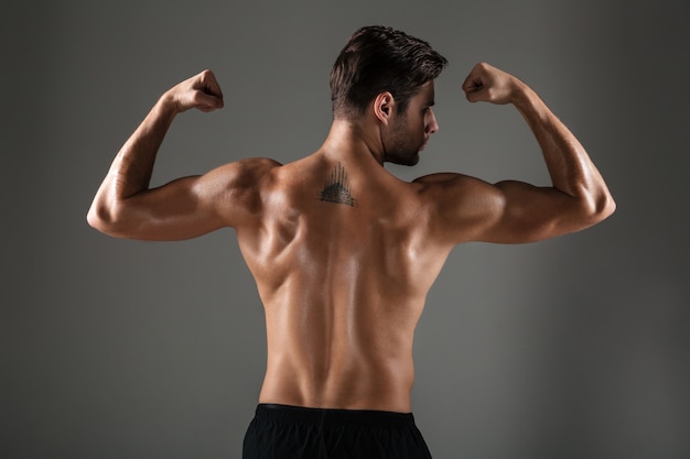 Free photo back view image of young sports man showing biceps