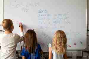 Foto gratuita bambini di vista posteriore che scrivono sulla lavagna