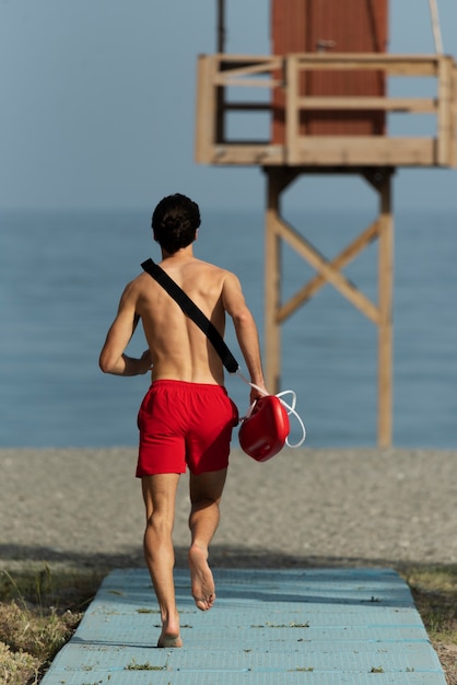 Back view lifeguard running on beach