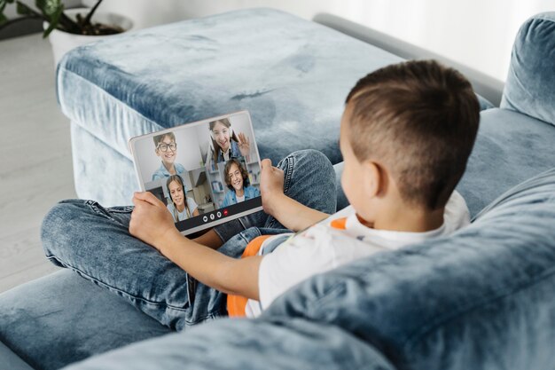 Back view of little boy talking to his friends through video call