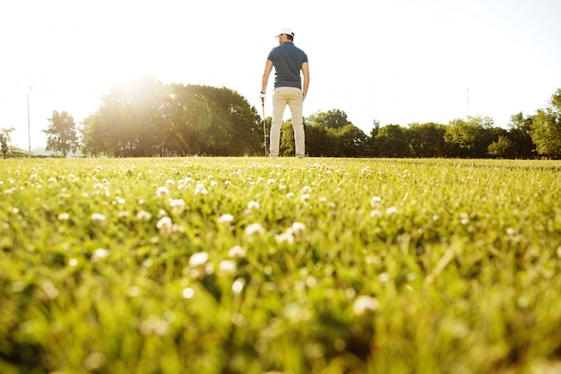 クラブと緑のコースで男性のゴルフプレーヤーの背面図