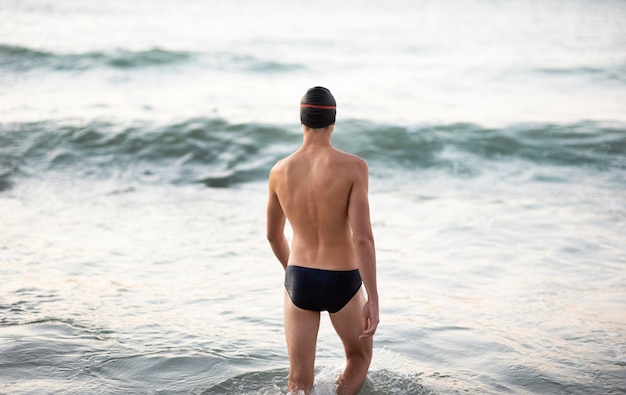 Back view of male swimmer getting in the ocean