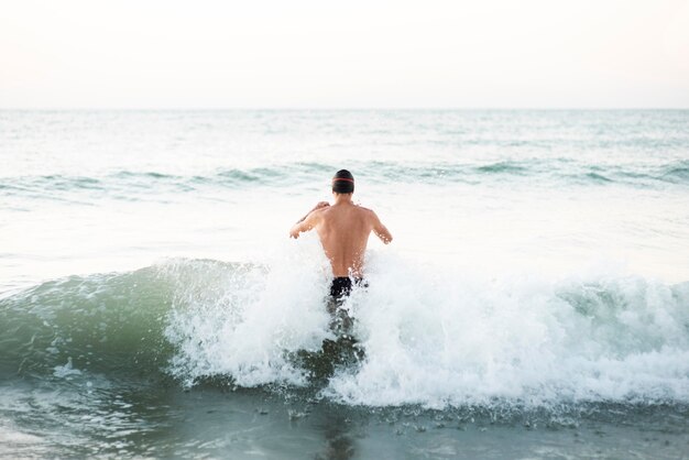 Back view of male swimmer getting in the ocean