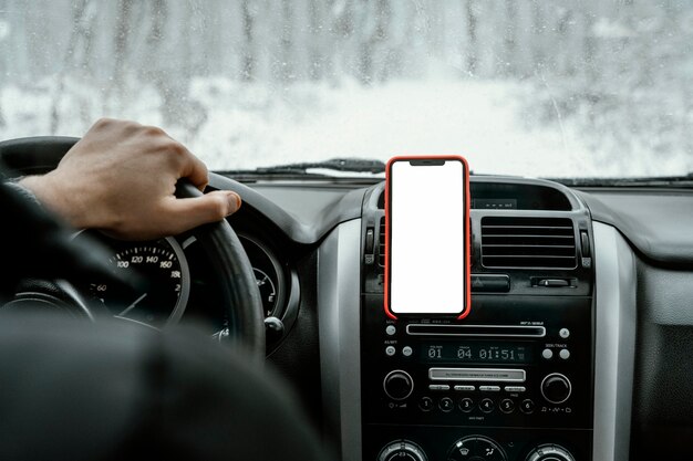 Back view of man driving the car for on a road trip with smartphone