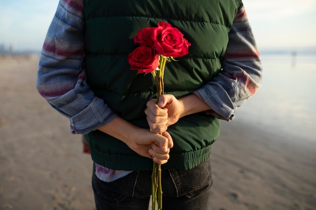 그의 데이트를 위한 깜짝 선물로 장미 꽃다발을 숨기고 있는 남자의 뒷모습
