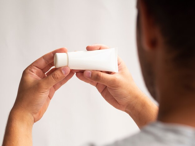 Free photo back-view man holding lotion bottle mock-up