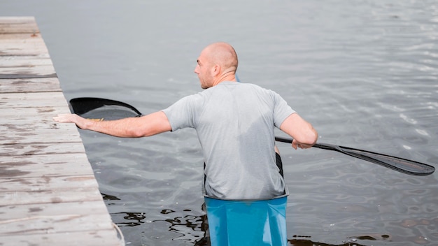 Foto gratuita vista posteriore uomo in kayak con pagaia