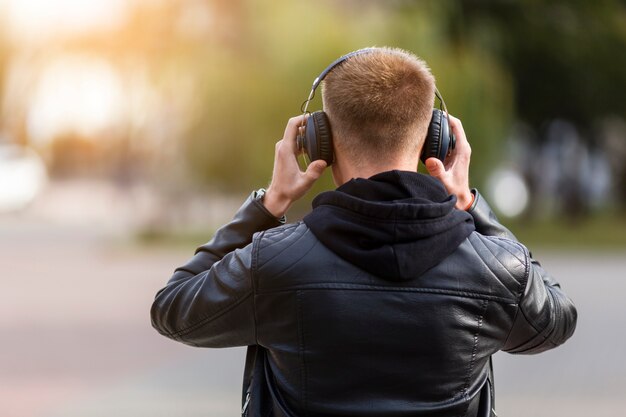 Back view man listening to music on headphones