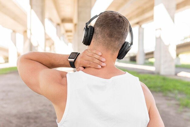 Back view man listening to music through headphones before training