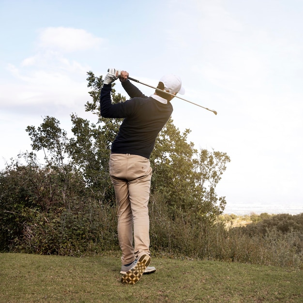 Free photo back view of man playing golf